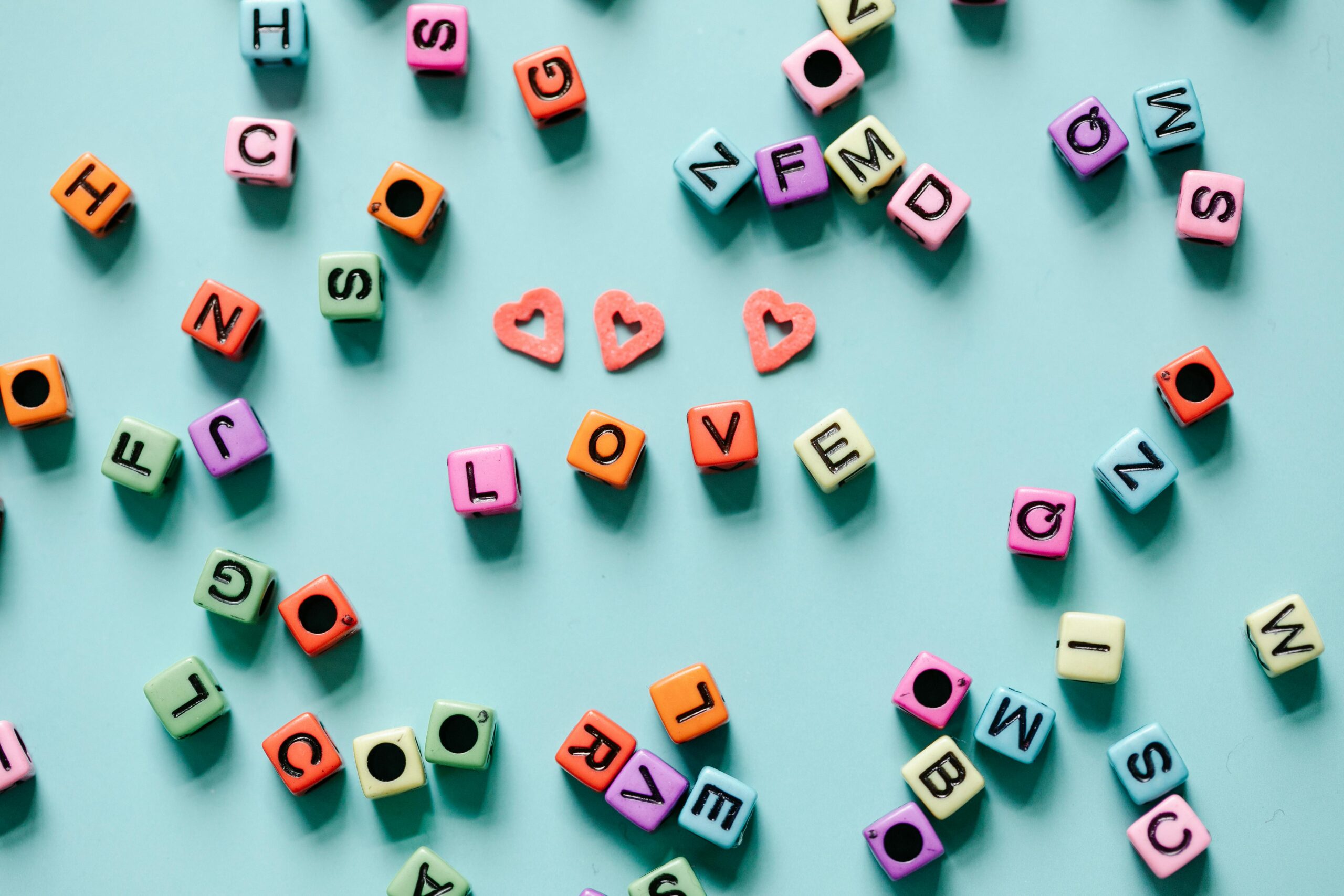 Colourful letter beads on a teal surface