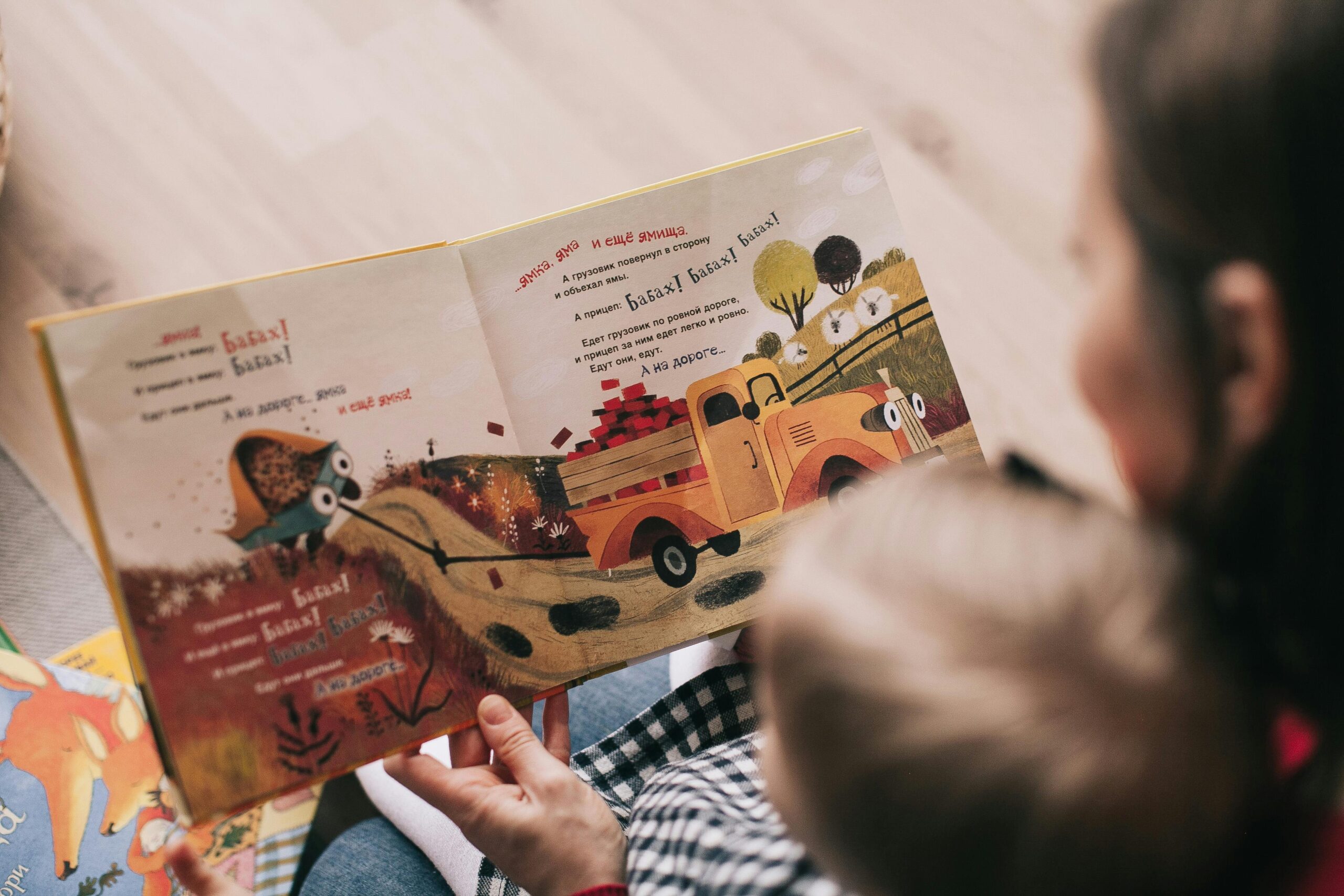 A parent reading a picture book in a minority language with their young child